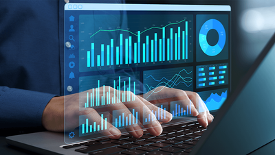 Hands typing infornt of a computer with data visualization graphs